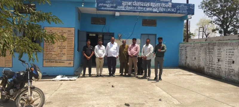 नीले पंचायत भवन के बाहर खड़े सात लोग; बोर्ड पर ग्राम पंचायत थूना कलां